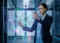 Une ingénieure manipulant une interface holographique de données numériques dans un centre de serveurs.