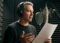 Comédien voix off lisant un script devant un micro de studio dans une cabine insonorisée