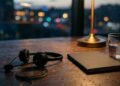 Casque de centre d’appels posé sur un bureau en bois au crépuscule, à côté d’un carnet et d’un verre d’eau