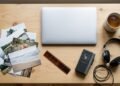 Vue de dessus d’un bureau avec ordinateur portable fermé, tirages photo, film négatif, dictaphone, casque et tasse