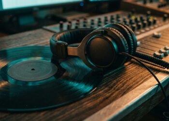 Disque vinyle et casque de studio posés sur une console de mixage