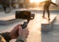 Vidéaste qui filme un skateur au smartphone sur stabilisateur, au coucher du soleil, pour une vidéo courte