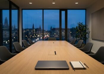 Salle de réunion vide au crépuscule, ordinateur portable fermé et carnet sur la table